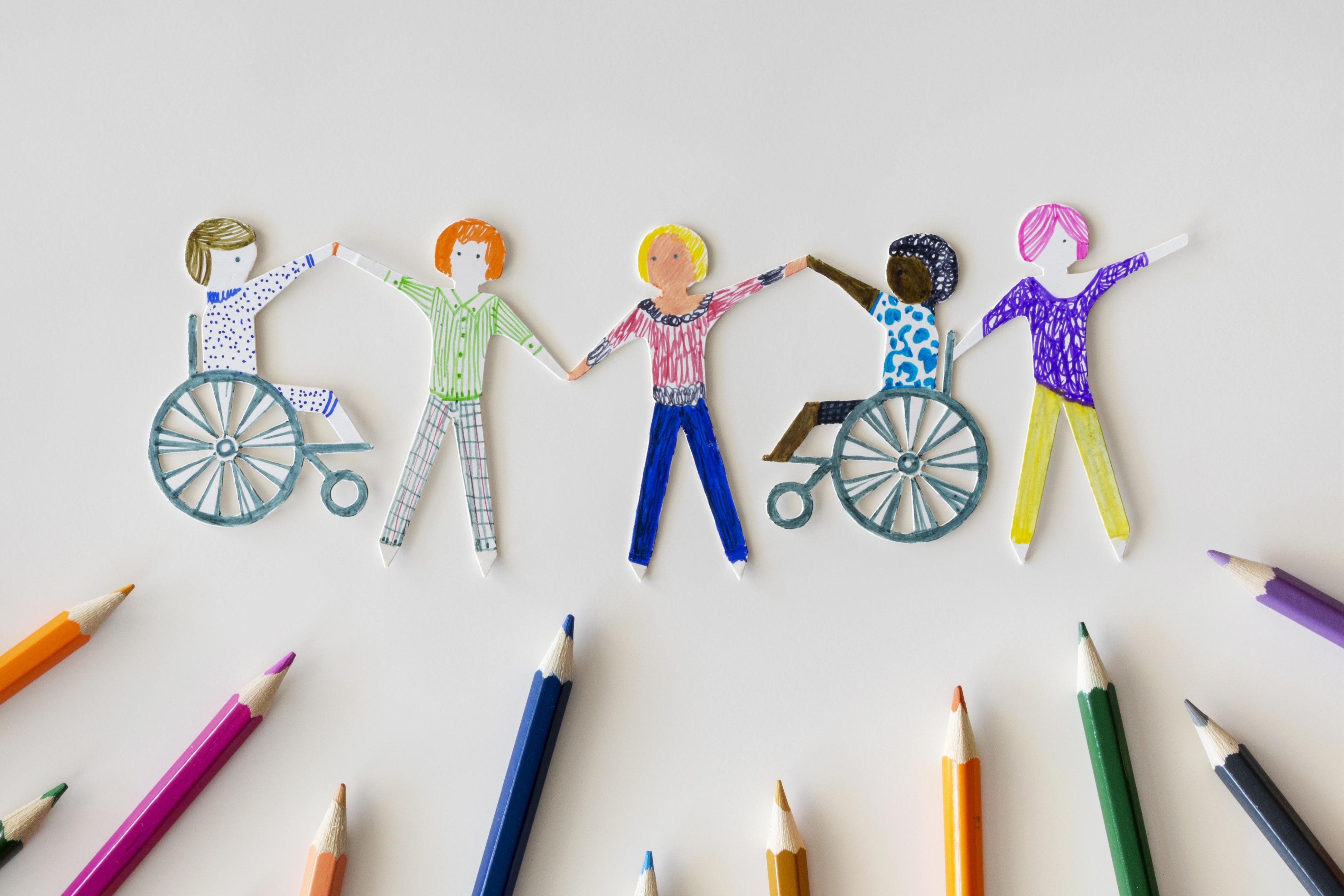 A diverse group of paper people in a line, holding hands, with pencil crayons below.