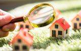 mini block houses being looked at by a hand holding a magnifying glass