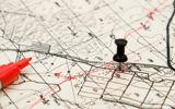 A map with red marker lines on this, with a push pin marking a property and a red marker laying on top of the map