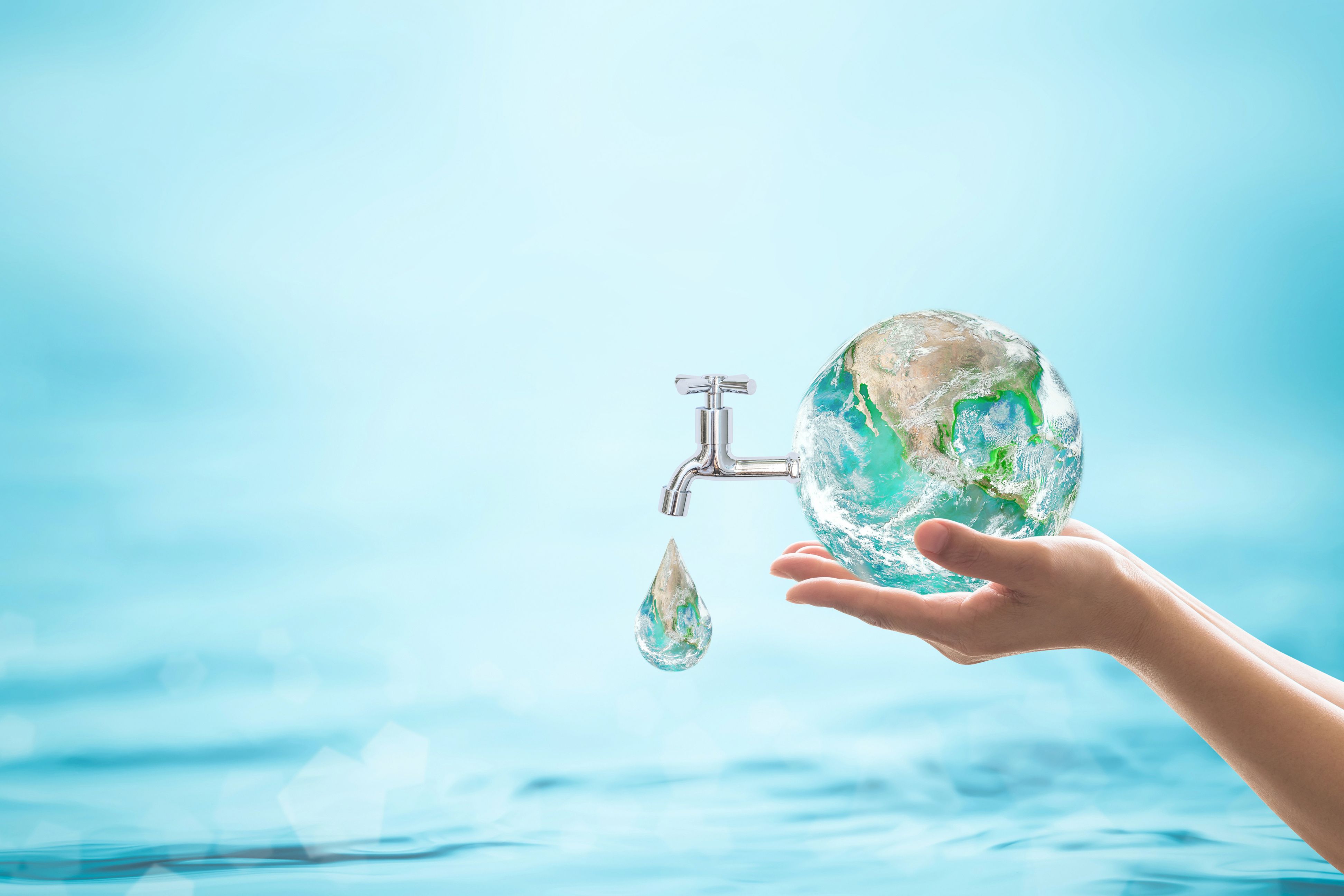 Blue water background with a hand holding a globe of water, with a tap attached and a drop coming out ot the tap.